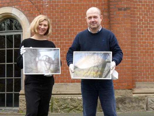 Vanessa Leissring, Lehrerin der Werner von Siemes-Schule, mit Dr. Jörg Schmitz und Bildern des Schulprojekts „CameraObscura-BlackBox”, die 2022 in der Camera Obscura ausgestellt wurden 