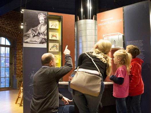 Familie und Museumsleitung an der Anamorphose im Museum zur Vorgeschichte des Films in der Camera Obscura Mülheim