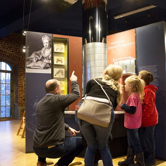 Familie und Museumsleitung an der Anamorphose im Museum zur Vorgeschichte des Films in der Camera Obscura Mülheim