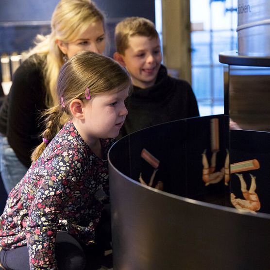 Familie an einer Wundertrommel (Zoetrop) im Museum zur Vorgeschichte des Films in der Camera Obscura Mülheim 