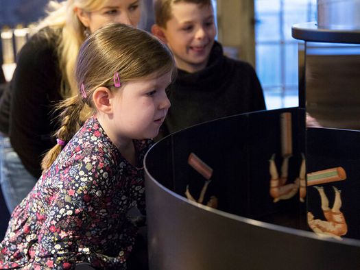 Familie an einer Wundertrommel (Zoetrop) im Museum zur Vorgeschichte des Films in der Camera Obscura Mülheim 